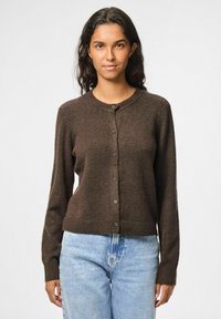 Cardigan marrone con scollatura rotonda, maniche lunghe e chiusura con bottoni davanti. Realizzato in materiale morbido, presenta un orlo a coste.
