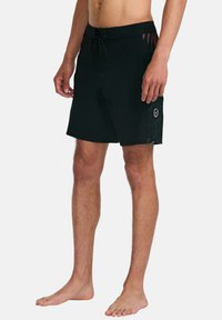 Black swim trunks featuring a drawstring waist, side graphics in teal, and a small logo patch on the left thigh. Smooth fabric texture.