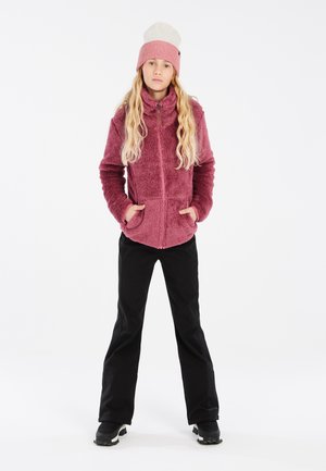 Veste en polaire mauve avec une capuche, fermeture éclair et poches avant, associée à un pantalon noir et un bonnet en tricot rose clair.