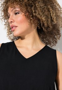 Černý top bez rukávů s véčkovým výstřihem, vyrobený z hladké tkaniny. Disponuje čistou siluetou a jemným leskem.