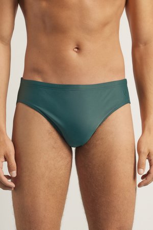 Bañador verde con un acabado suave y brillante. Presenta un diseño de cintura baja y costuras mínimas para una apariencia aerodinámica. Sin patrones ni elementos metálicos.