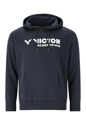 Lyshåret mand iført en mørkeblå hættetrøje med "VICTOR READY TO WIN" logo, stående mod en ensfarvet lys grå baggrund.