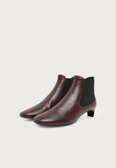 Paire de bottines en cuir marron avec panneaux latéraux élastiques noirs et petits talons carrés sur fond blanc.