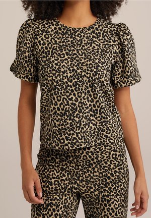Woman wearing matching leopard print short-sleeve top with puffed sleeves and high-waisted pants against neutral background.