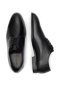 Czarne skórzane buty do garnituru z gładkim wykończeniem, sznurowanym designem i dekoracyjnymi perforacjami po bokach. Niski płaski obcas.