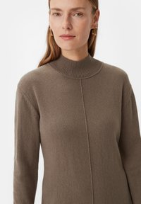 Strickpullover in einem gedämpften Braunton, mit hohem, geripptem Kragen, langen Ärmeln und einem schlichten Design mit subtilen Texturdetails.