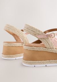 Wedgesandalen met beige gevlochten jute bandjes, roze suède verstelbare enkelbandjes, houten plateau en witte rubberen zool.