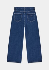 Wijde denim jeans in donkerblauw met twee achterzakken, witte stiksels en het 'GUESS' logo geborduurd op de rechterzak.