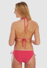 Bikini rose rembourré avec un col halter et des liens à nouer. Le haut présente un design triangulaire classique, et le bas a des liens sur les côtés.