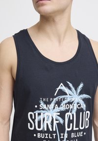 Černý bavlněný tílko s grafickým potiskem palem a nápisem "THE PERFECT WAVE SANTA MONICA SURF CLUB" v bílé a světle modré barvě.