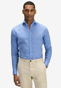 Ljusblå långärmad skjorta i texturerad väv, med button-down krage och manschetter. Bärs med beige byxor.