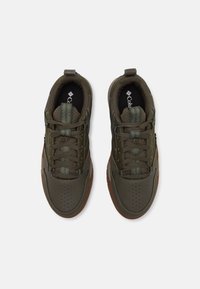 Ciemnozielone sneakersy z perforowanym wzorem, teksturowanymi akcentami i gumową podeszwą. Posiadają wzorzystą język i brązową podeszwę.