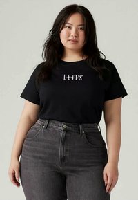 Tricou scurt negru cu mânecă scurtă, având logo-ul "LEVI'S" alb pe piept, asociat cu blugi gri închis cu talie înaltă. Material din bumbac moale.