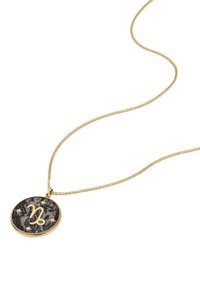 Collana dorata con un pendente rotondo caratterizzato da un design marmorizzato nero e un simbolo zodiacale inciso circondato da piccole stelle.