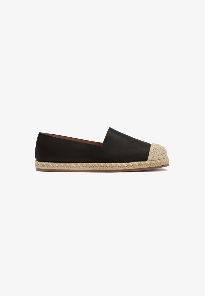 Chaussure plate noire à enfiler avec bout beige tissé et semelle en jute tressée, conçue pour un usage décontracté.