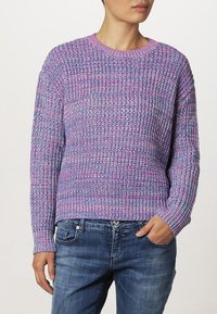 Maglione lavorato a maglia in tonalità di viola e blu, con colletto rotondo, maniche lunghe e un motivo testurizzato. Abbinato a jeans blu.