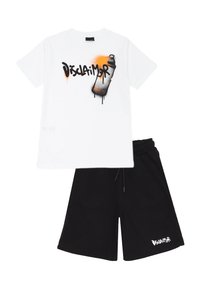 T-shirt bianca in cotone con grafica di una bomboletta spray nera e arancione e testo "Disclaimer". Abbinata a pantaloni corti neri con logo bianco.