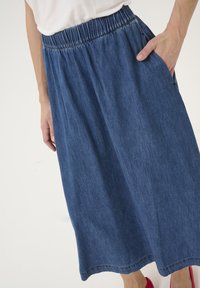 Jeans midi krilo z elastčnim pasom, stranskimi žepi in mehkim, teksturiranim materialom v globoko modri barvi.