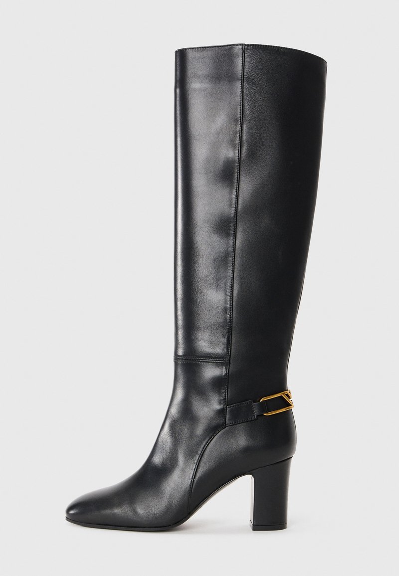 Black leather knee-high boot with a pointed toe and a chunky heel. Features a gold-tone accent strap around the ankle. Smooth texture.
