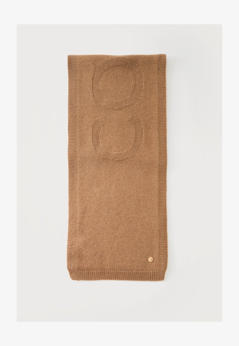 Écharpe en tricot marron pliée avec des motifs circulaires en relief et un petit emblème rond doré près du bord sur un fond blanc.