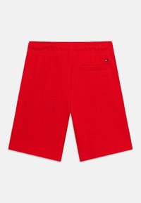 Κόκκινα σορτς μήκους μέχρι το γόνατο με ελαστική μέση και μια πίσω τσέπη που φέρει ένα μικρό λογότυπο με σημαία σε μαύρο, λευκό και κόκκινο χρώμα.