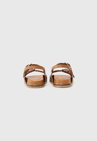 Brune sandaler med to stropper, vevd tekstur og flat såle. Har metallhardware detaljer. Glatt innersåle.