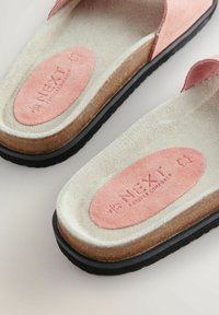 Ružičaste suede sandale s podstavljenim gazištem, teksturiranom bež unutrašnjosti i crnom gumenom potplatu. Sadrže urezanu marku.