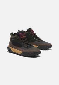 Scarpe outdoor alte con rete nera e pelle, dettagli viola e suola in gomma nera robusta con battistrada pronunciato per una migliore aderenza.