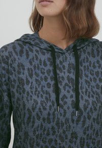 Felpa con cappuccio blu con un motivo a stampa leopardata nera. Presenta un cordino con punte argentate e un tessuto morbido e testurizzato.
