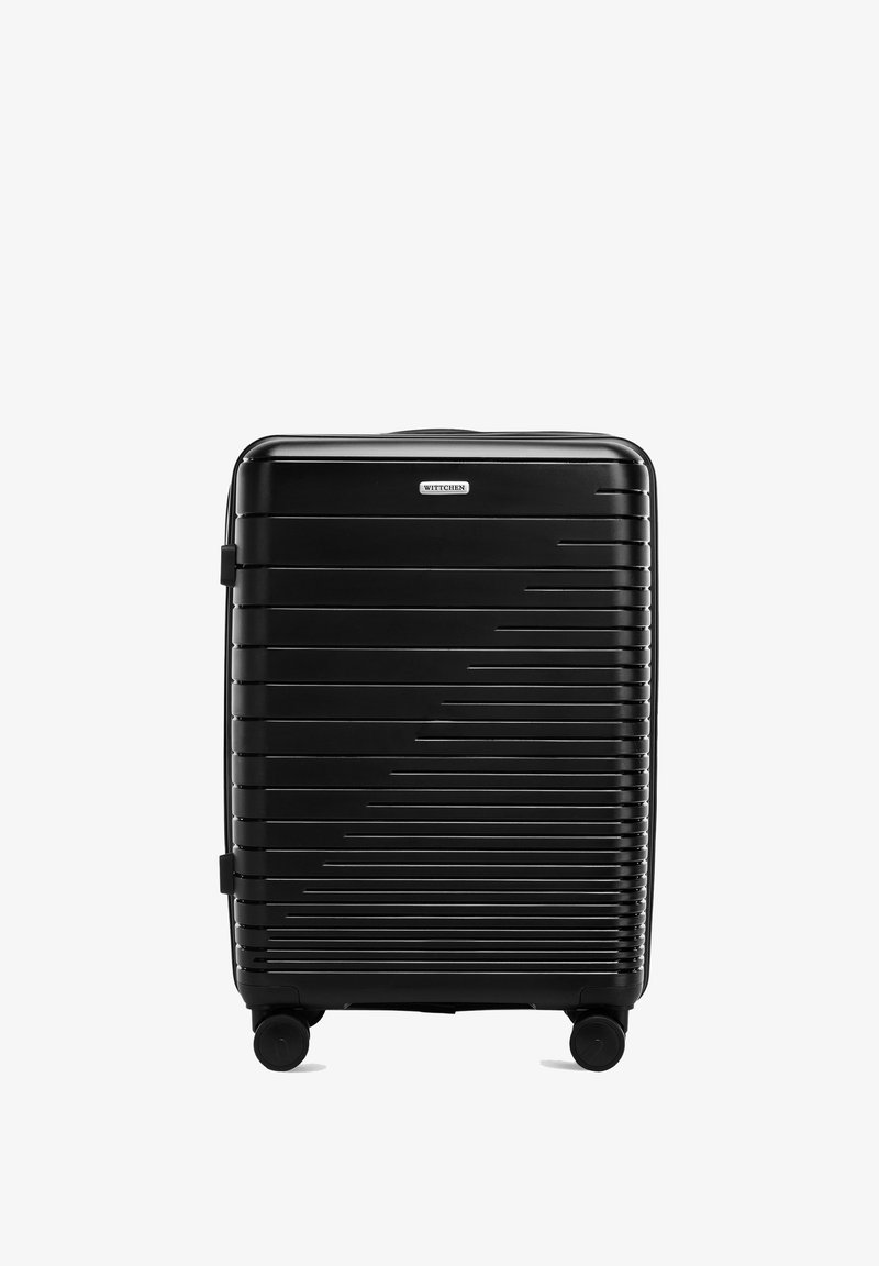 Valise rigide noire avec des lignes horizontales, dotée d'une texture lisse, d'une poignée télescopique et de quatre roues pour une mobilité facile.