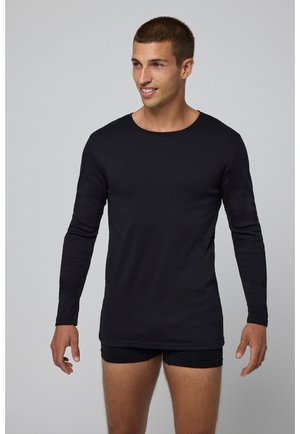 Camiseta negra de mangas largas en un diseño ajustado, hecha de tejido suave. Presenta un escote redondo y un dobladillo recto con costuras mínimas.