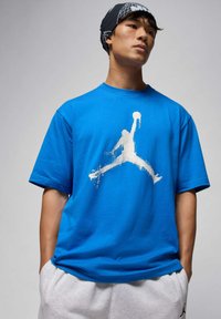 Blaues Baumwoll-T-Shirt mit großem weißem Jordan-Logo, kurzen Ärmeln und lockerer Passform. Lässiges Design mit weicher Textur.