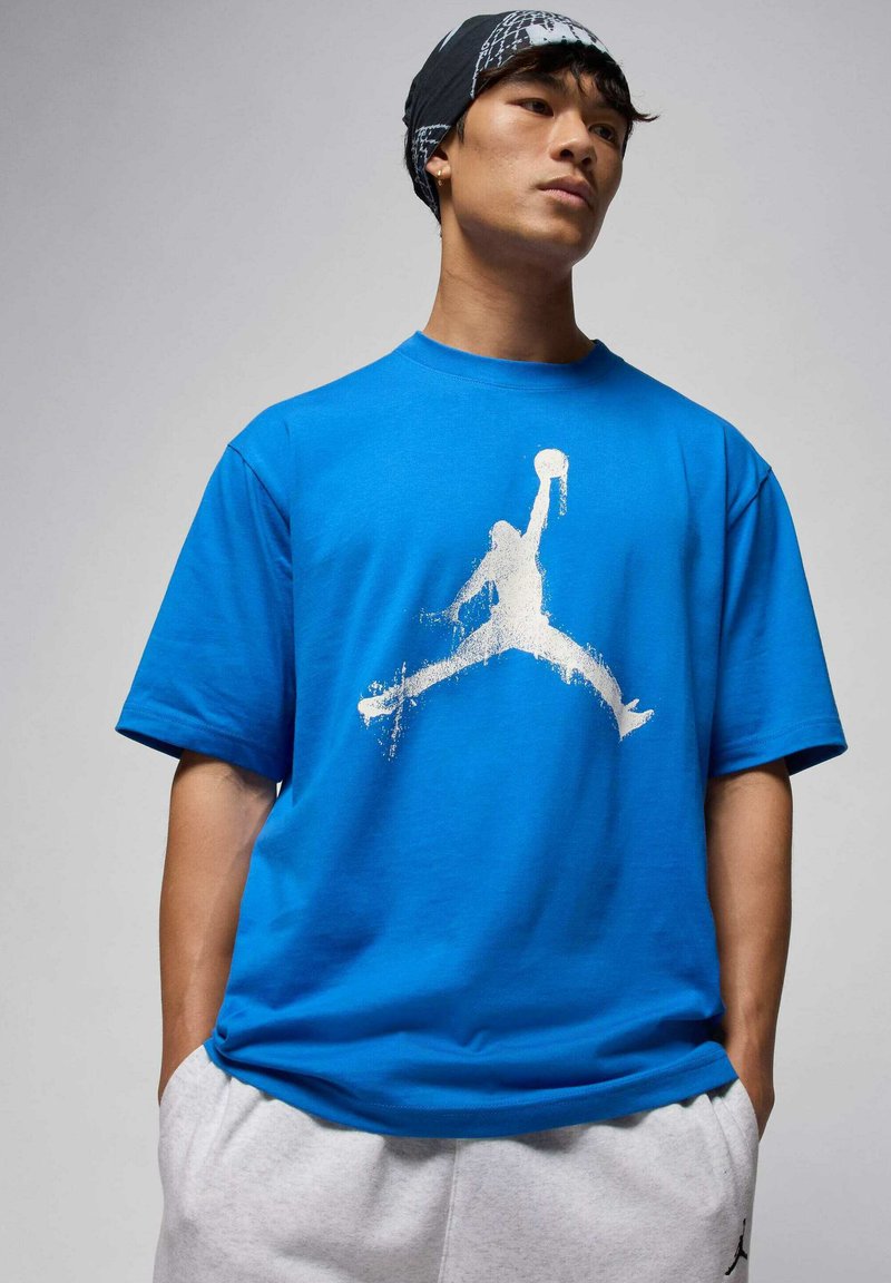 Blaues Baumwoll-T-Shirt mit großem weißem Jordan-Logo, kurzen Ärmeln und lockerer Passform. Lässiges Design mit weicher Textur.