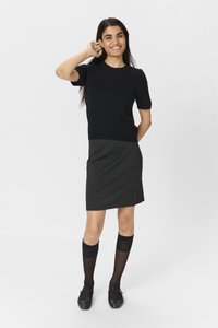 Sort kortærmet sweater parret med en mørk houndstooth nederdel, knæhøje strømper og flade sorte sko. Enkel, tætsiddende design med teksturerede detaljer.