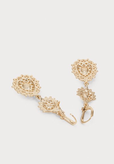 Pendientes colgantes en tono dorado con un diseño floral similar al encaje. Presenta detalles intrincados de filigrana y un cierre de palanca seguro.