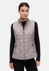 Gequilted, licht taupe vest met hoge kraag, voorrits en twee ritszakken aan de zijkant. Heeft een gestructureerd patroon en een slank ontwerp.