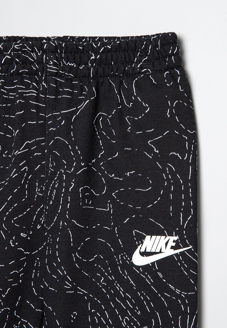 Czarne dresy z fakturowanym wzorem białych linii, z elastycznym pasem w talii i białym logo Nike w lewym dolnym rogu.