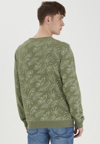 Sudadera verde oliva con un patrón de hojas, puños y dobladillo acanalados, cuello redondo y textura suave. Vista trasera del diseño.