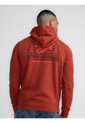 Roter Kapuzenpulli mit schwarzem Grafikdesign, das Bäume und den Text "PETROL INDUSTRIES" sowie "BIG LAKE ALASKA '89" auf der Rückseite zeigt.