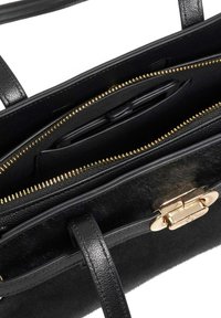 Black handbag with smooth leather and soft fur texture. Gold zipper accents and closure, featuring multiple compartments for organization.