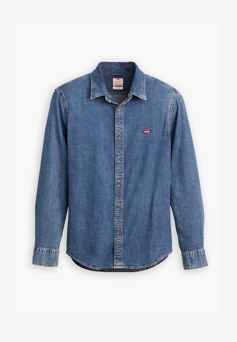 Chemise en denim bleu foncé avec un col boutonné, des manches longues, des accents cousus et un petit logo rouge sur la poche de la poitrine.