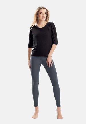 Black, loose-fitting top with 3/4 sleeves paired with form-fitting, dark gray leggings in a smooth, stretchy material.