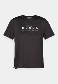 Camiseta atlética negra hecha de tejido ligero, con cuello redondo, mangas cortas, aberturas laterales y un diseño de logo gráfico.