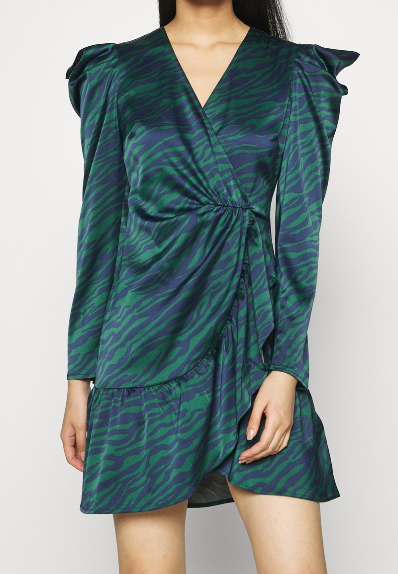 Green and navy wrap dress with tiger stripes; features long sleeves, a gathered waist, and layered ruffled hem. Made from a smooth fabric.
