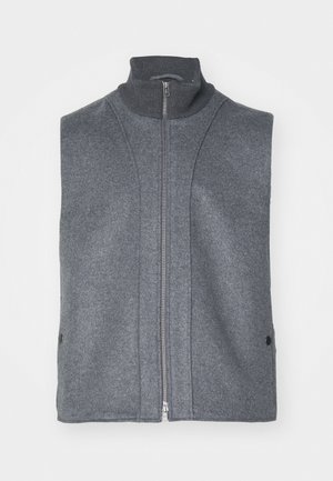 Pelēks bez piedurknēm bezmaksas žakets, kas izgatavots no teksturēta vilnas līdzīga materiāla, ar augstu apkakli un priekšējo rāvējslēdzēju, kā arī sānu pogu akcentiem.