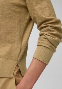 Maglione beige lavorato a maglia con polsini a coste testurizzati e spacco laterale. Il tessuto ha una finitura morbida, caratterizzato da una vestibilità comoda.