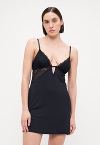 Fekete hálóruha csipkebodóval, V-kivágással, állítható pántokkal és kulcslyuk részlettel elöl. Sima anyagtextúra.