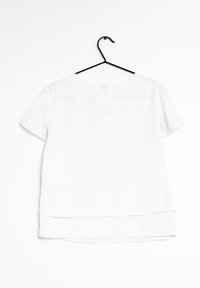 Vit kortärmad blus på en svart galge. Slät tyg med lagerdrapering i nederkant och rund halsringning. Minimalistisk design utan mönster.