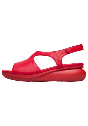Red leather sandal with an open toe and cutout design. Features a curved wedge sole for support and an adjustable strap at the heel.