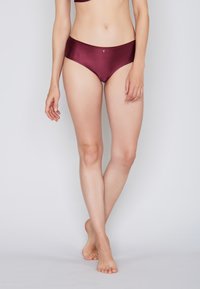 Burgunderrote Bikinihose mit geripptem Strukturmuster und niedrigem Bund. Verfügt über ein kleines Logo vorne als Akzent.